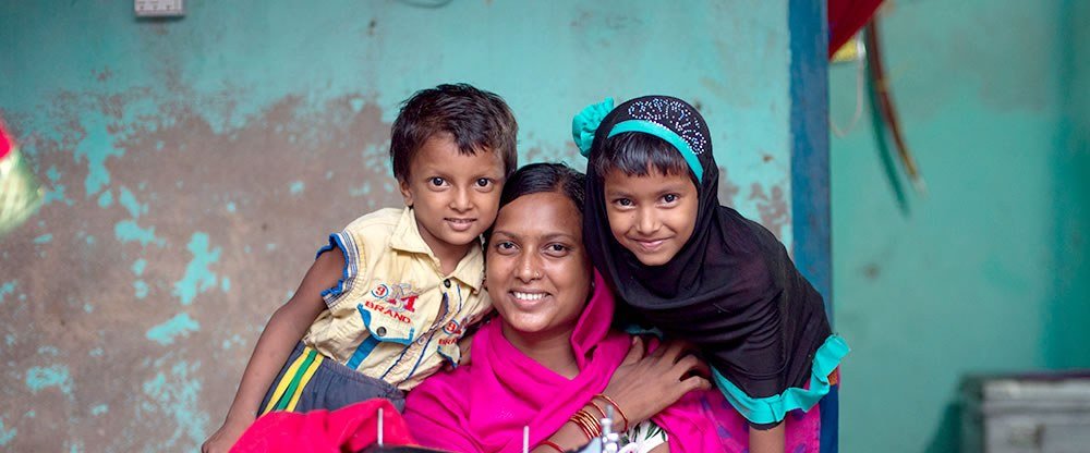 A mother with her two children at her sewing machine