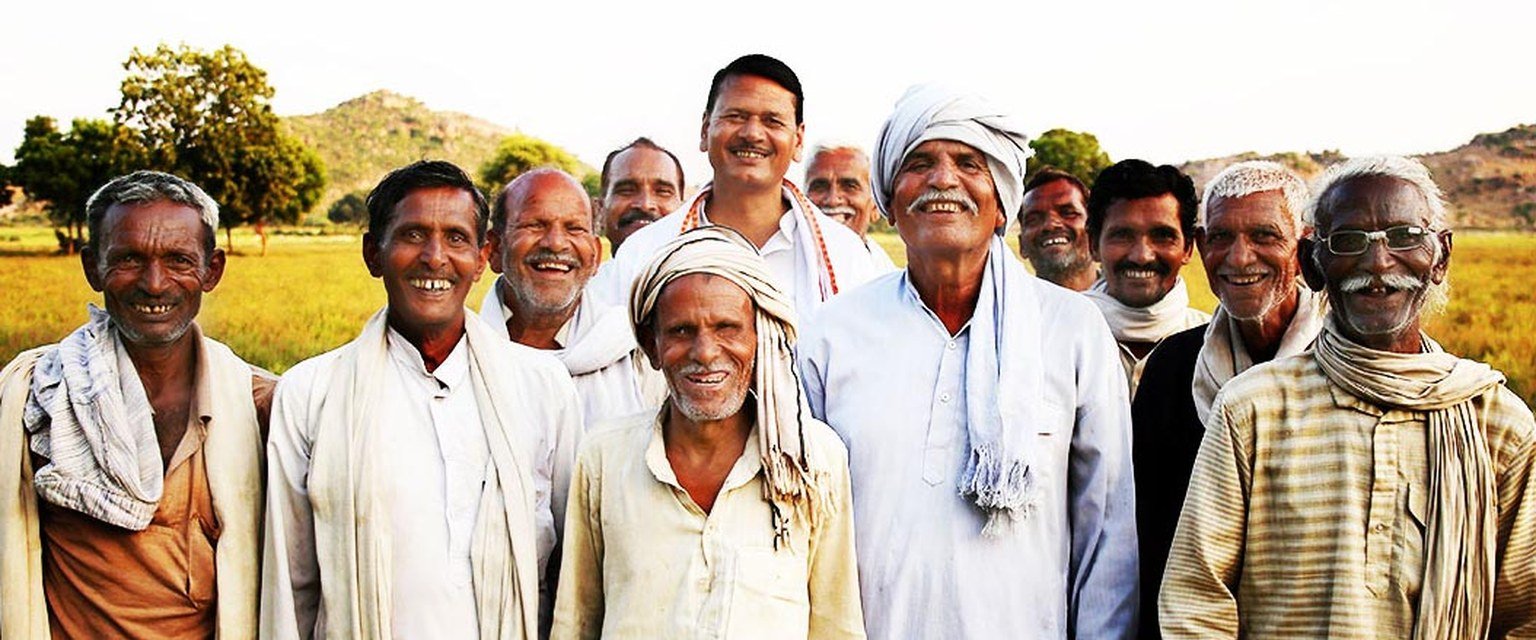 A group of smiling farmers standing together in a field, part of an Ubantu Foundation cooperative