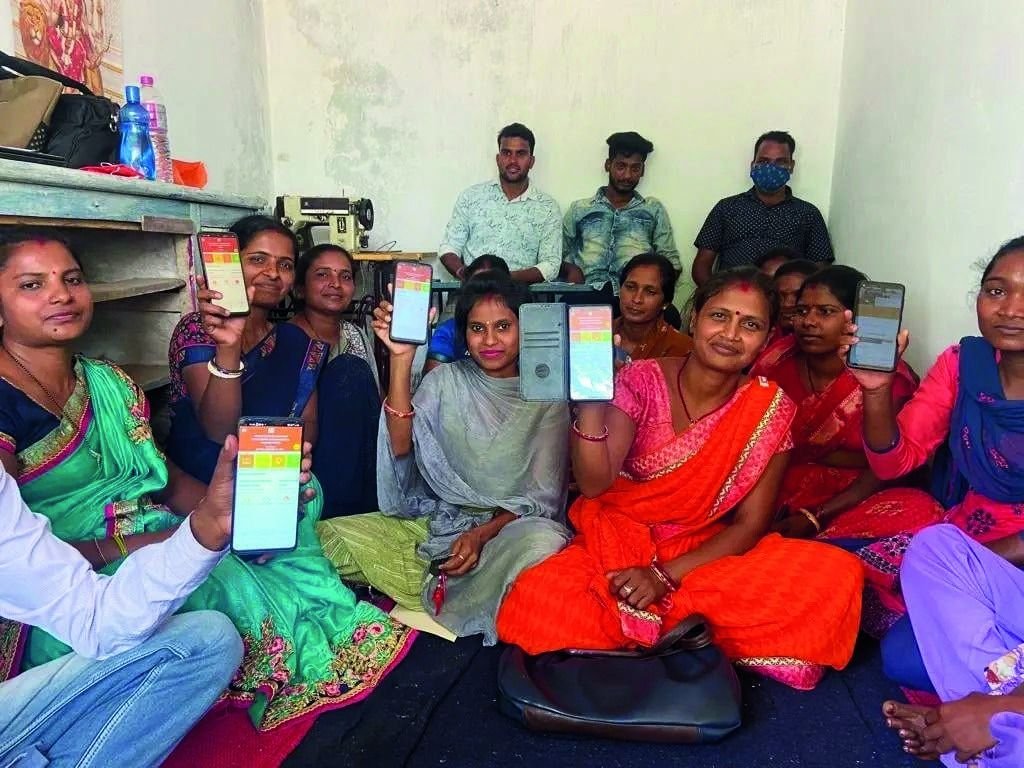 Self-help group members holding up phones showing a mobile banking app