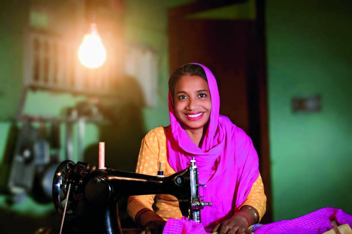 A woman smiling at her sewing machine in an Ubantu Foundation livelihood centre