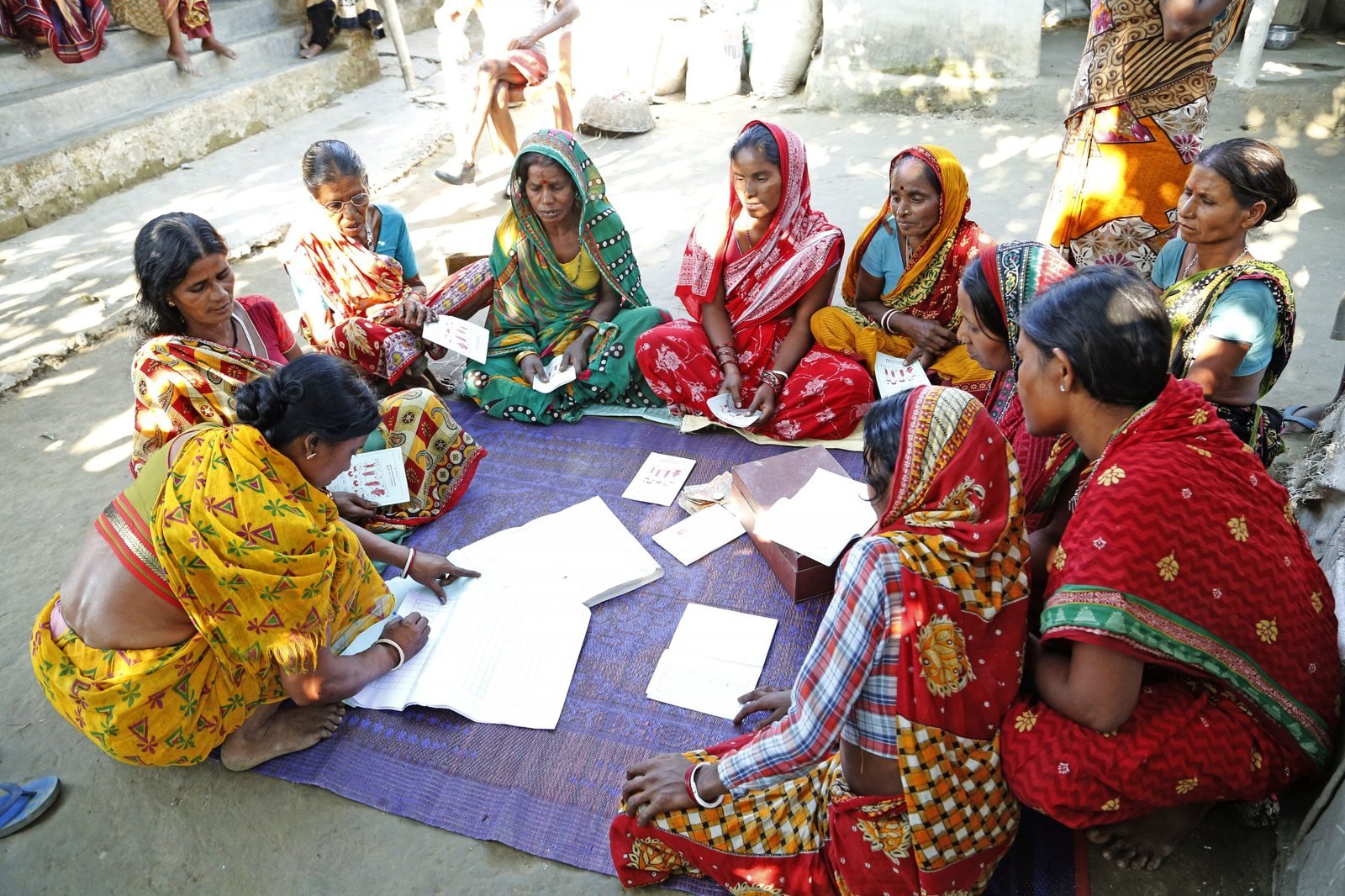 Self-help group members reviewing their shared records together during a group meeting