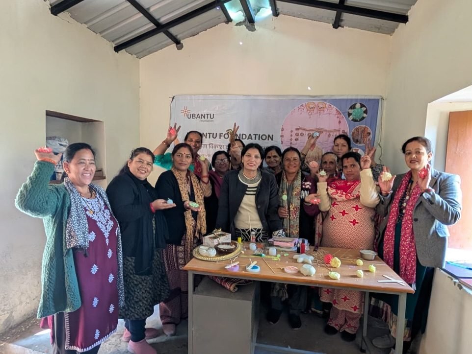 Training participants holding up candles they made, in front of an Ubantu Foundation banner