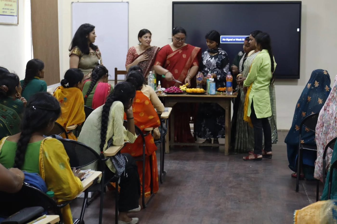 A trainer demonstrating bio-enzyme preparation to women seated in a training room